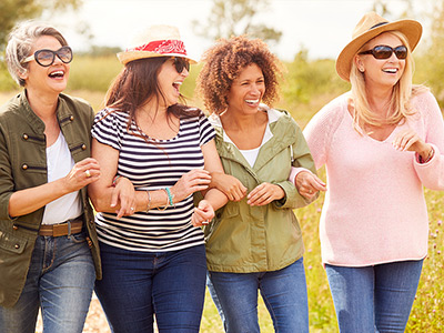 group of female friends laughing and walking through a park
