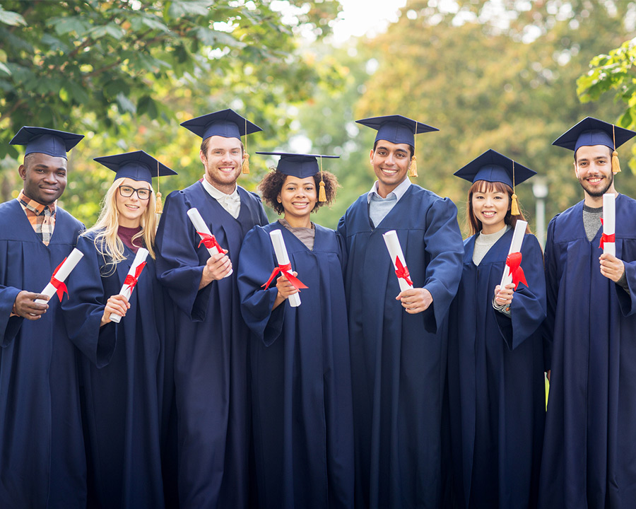 multi-cultural group of graduates in cap and gown with diplomas