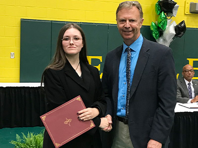 employee presenting a high school senior with a scholarship
