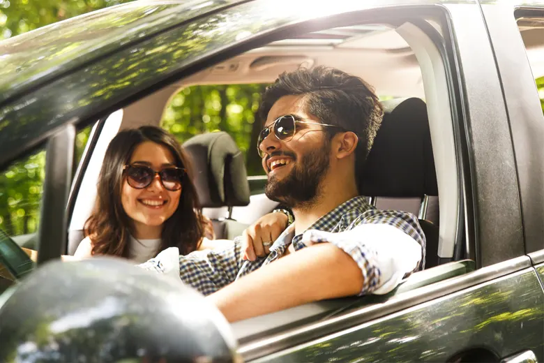 smiling man and woman driving car