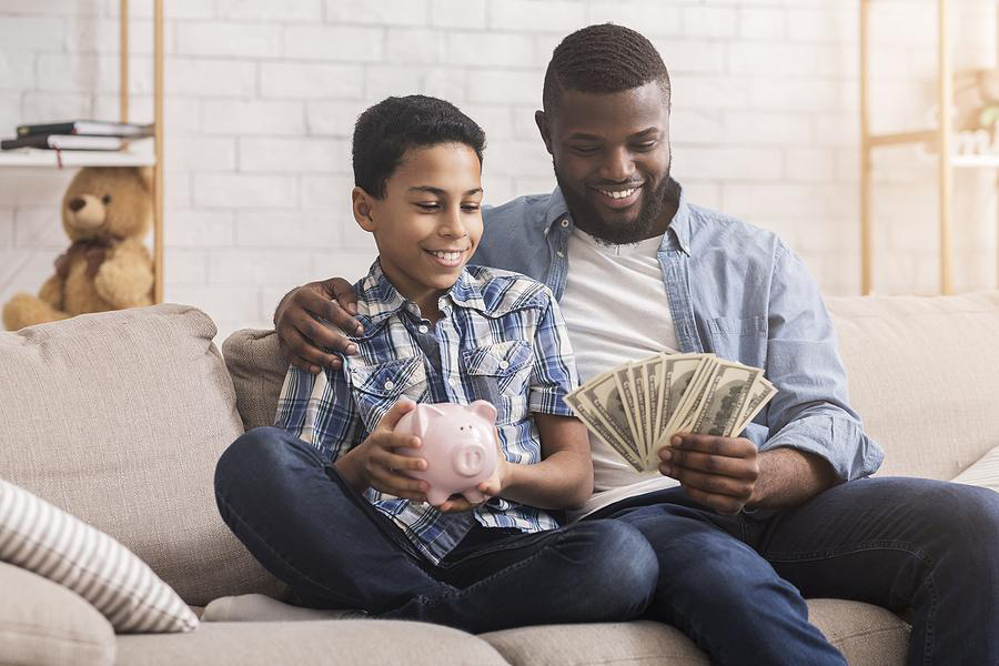 Father and son holding money and a piggy bank