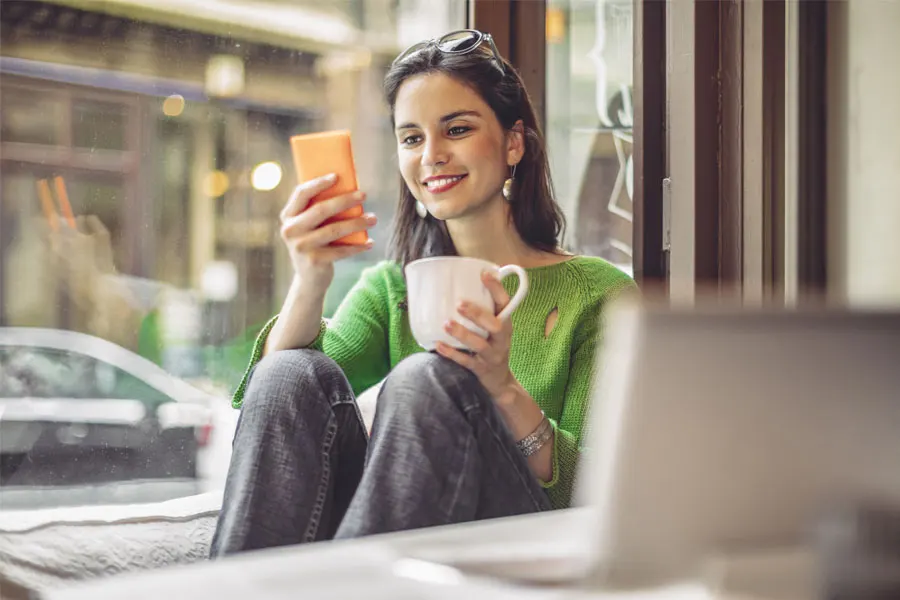woman drinking tea while checking her phone