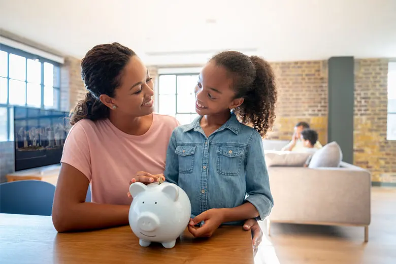 mother and daughter putting money in piggy bank