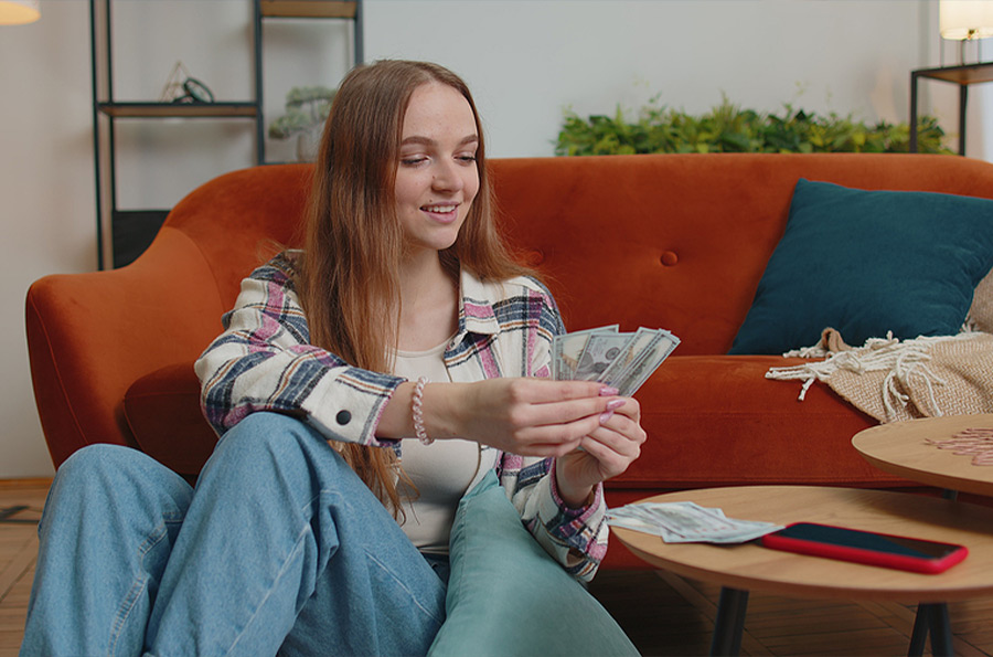 female teen counting money in her living room