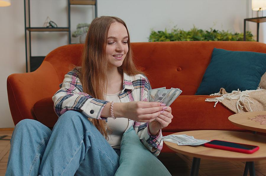 female teen counting money in her living room